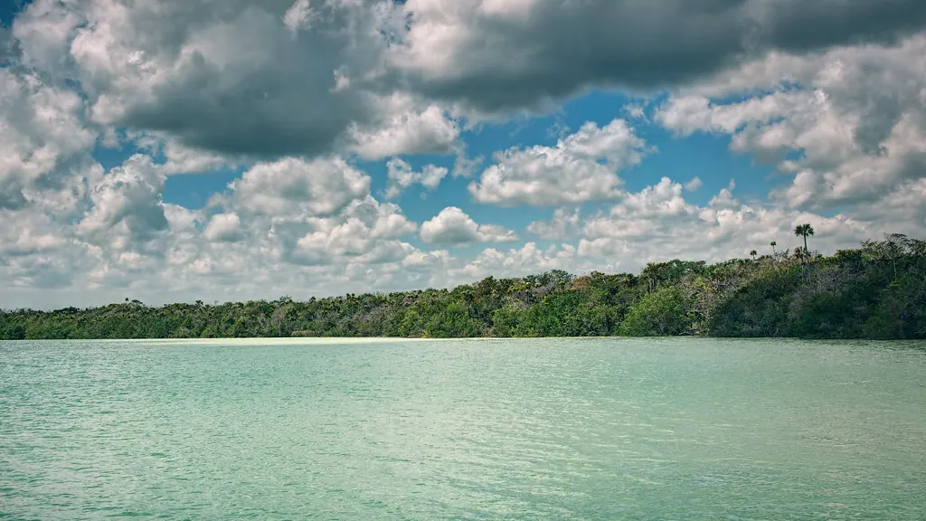 Vista de la Laguna de Kaan Luum: agua verde turquesa rodeada de selva bajo un cielo con nubes