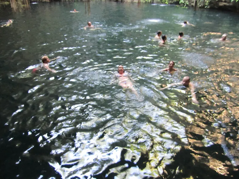 Personas nadando en un cenote de agua clara